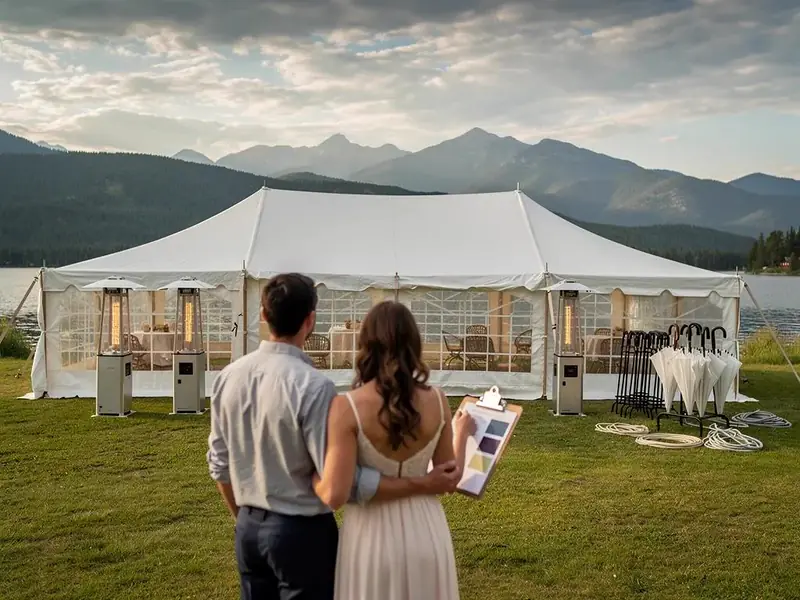 Two people with a clipboard of color swatches looking at a white tent with window walls and patio heaters