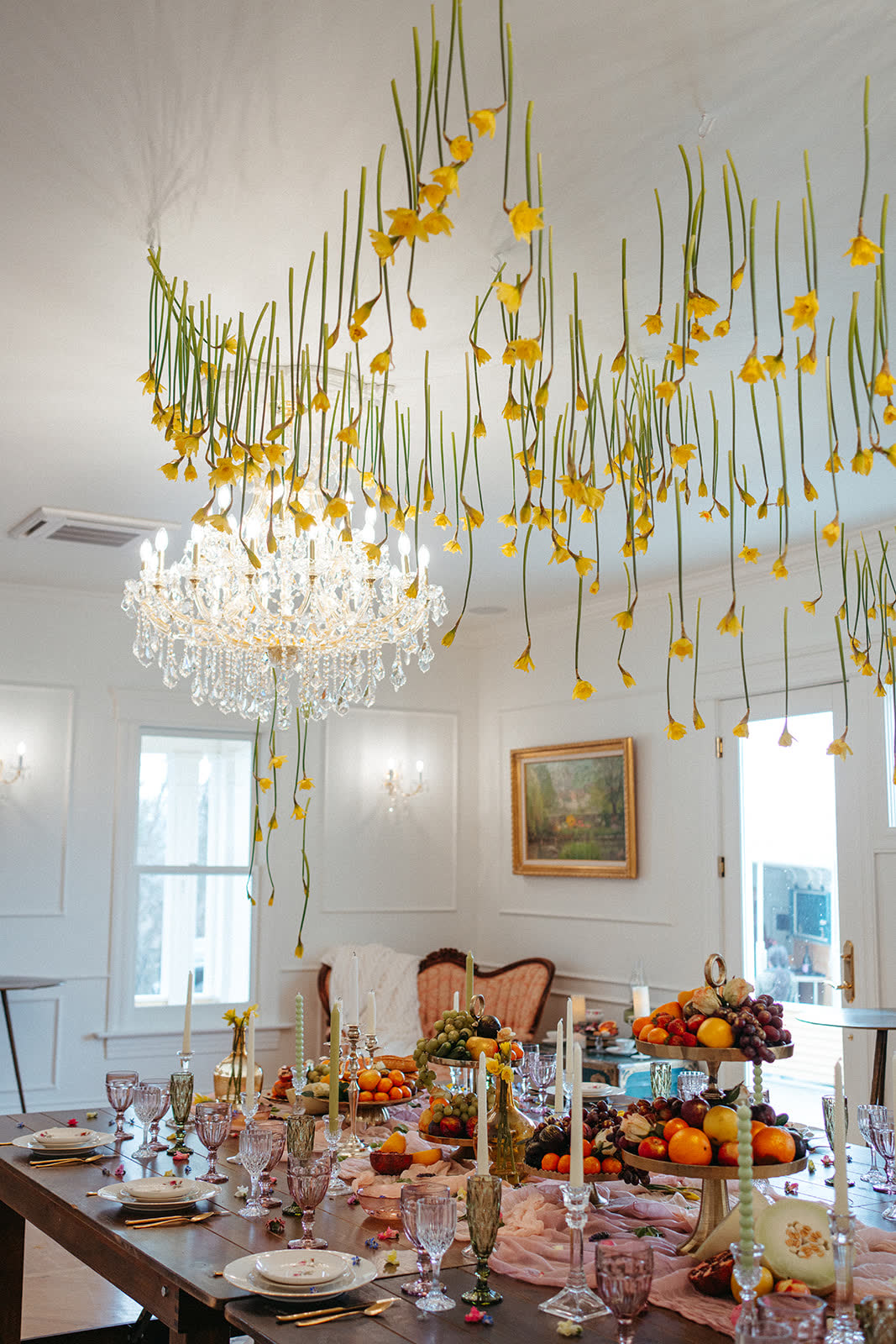 Reception room set with crystal chandeliers and hanging blooms over long tables