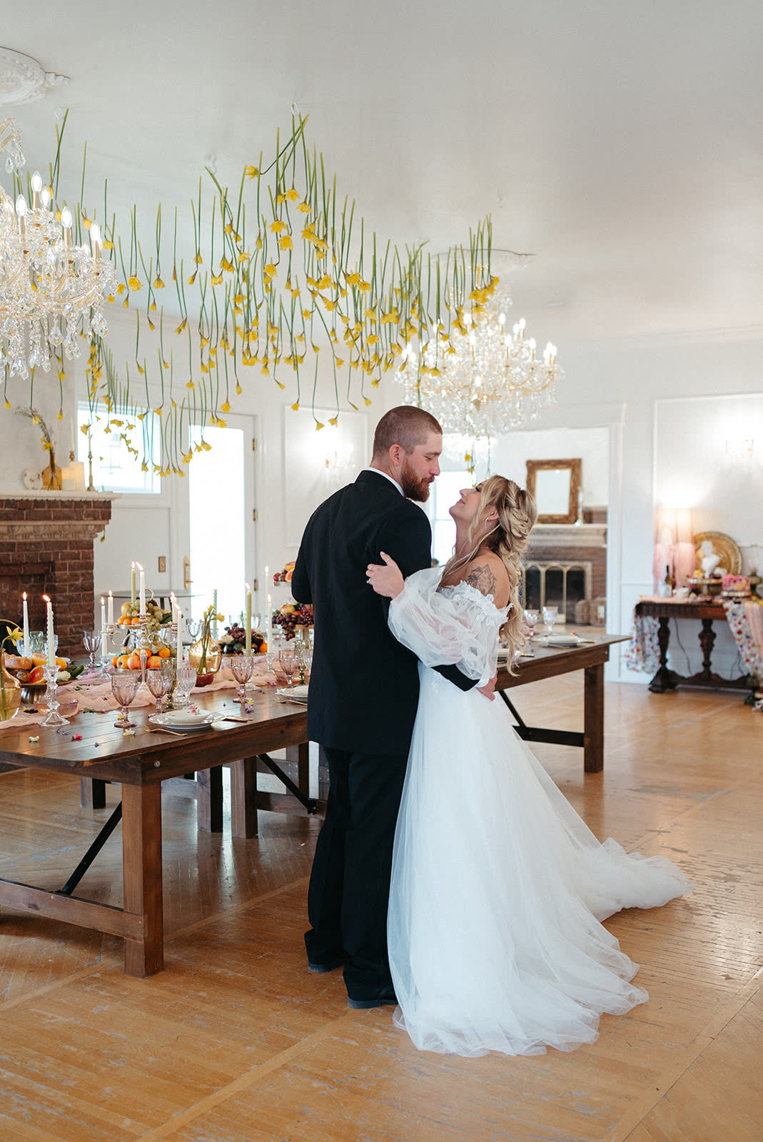 Couple dancing beside a set reception table under a crystal chandelier