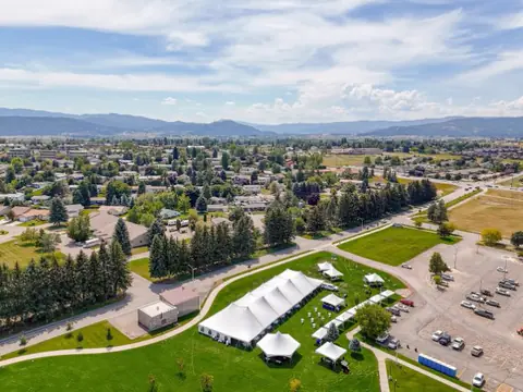White event tents in a green park seen from the air, with mountains in the distance