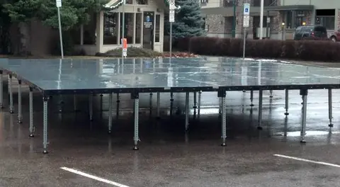 Modular stage sections set up outdoors on pavement for a show