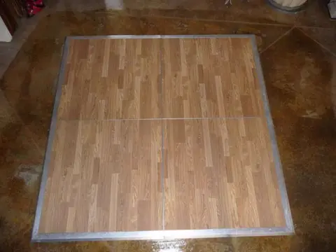 A square New England plank dance floor with a metal edge trim, laid out before an event A square New England plank dance floor with a metal edge trim, laid out before an event